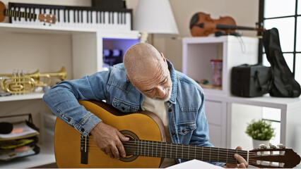 Wall Mural - Bald man in denim playing guitar in a room with musical instruments