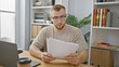 © Krakenimages.com - Focused young man with beard reading documents in modern office