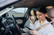 © SHOTPRIME STUDIO - Woman driving car and holding cell phone, looking at screen with hands on steering wheel, emphasizing distracted driving and mobile phone usage while operating vehicle