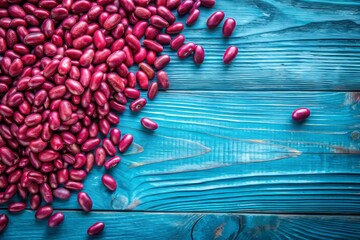 Vibrant pink beans scattered on a rustic blue wooden table, surrounded by empty space, ideal for adding text or logos, perfect for food or health related designs.