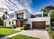 © Autun - Modern suburban home with sleek white stucco exterior and minimalist design elements, surrounded by lush greenery and open front yard on a sunny summer day.