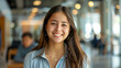 © Muhammad - Young smiling latin girl college student or teacher looking at camera standing in university campus. Happy hispanic millennial woman professional posing in modern coworking creative office space