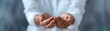 © Boontharika - A person holding out their cupped hands, isolated on a blurred background. The image conveys openness, giving, and an invitation to receive.