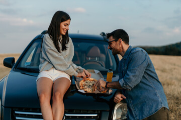 Sticker - Urban styled couple easting a slice of pizza on a car and enjoying the sunset