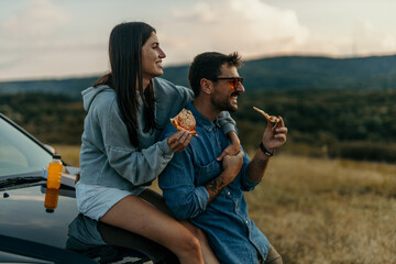 Canvas Print - Side view of a happy woman and man are eating and enjoying the road trip concept. copy space