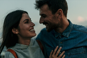 Wall Mural - Traveling couple standing outdoors together and laughing during an evening in the hills