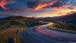 © poomrapee - Scenic winding road through rolling hills at sunset with stunning sky, showcasing motion blur of car lights emphasizing travel and adventure.
