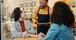 © peopleimages.com - Cafe, women and waiter order with tablet, conversation and customer service at restaurant. Barista, staff and happy girl friends with smile and chat at coffee shop with employee helping with tech