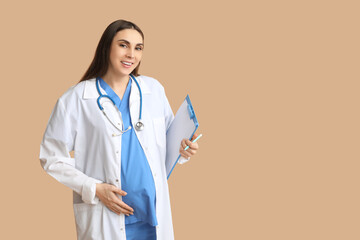 Wall Mural - Beautiful young pregnant doctor with clipboard on brown background