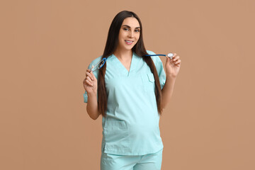 Poster - Beautiful young pregnant doctor with stethoscope on brown background