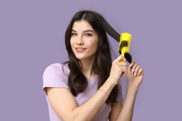 Poster - Beautiful young woman brushing her hair on lilac background