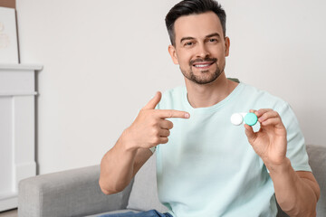 Wall Mural - Young man with contact lenses sitting on sofa at home