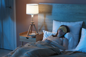 Wall Mural - Young pretty woman in mask sleeping on bed in bedroom at night