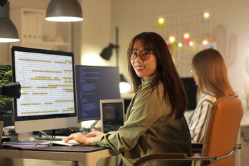 Poster - Female Asian programmer working in office at night