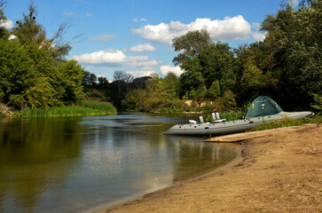 moored inflatable boat sits peacefully on the river bank while trees form a serene backdrop, creatin