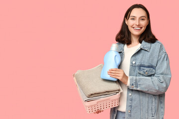 Canvas Print - Young woman with laundry basket and bottle of detergent on pink background