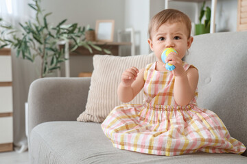 Wall Mural - Cute little baby with nibbler eating food on sofa at home