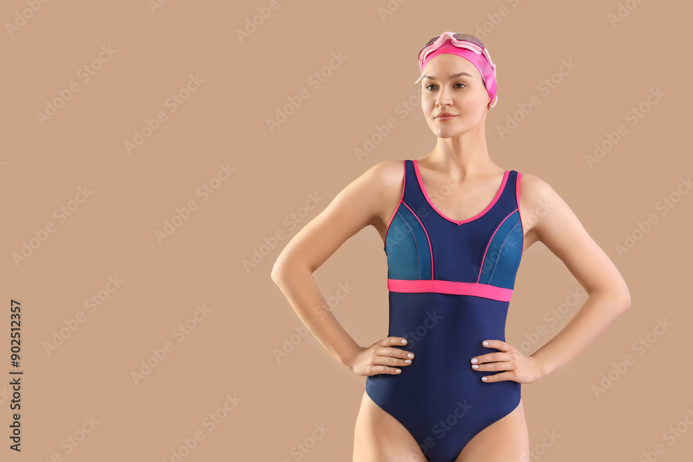 Professional young female swimmer on beige background