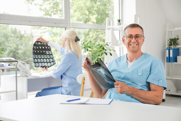 Wall Mural - Male doctor studying x-ray image at table in clinic