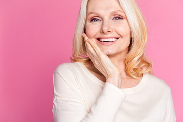 Wall Mural - Photo of cheerful positive senior woman dressed stylish clothes touch face empty space isolated on pink color background