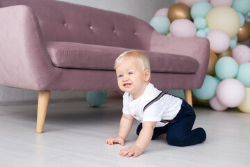 Little boy at home with strabismus eyes near sofa and baloons. Family and childhood concept, holiday