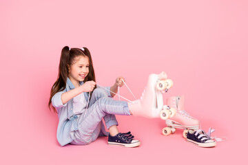 Poster - Full size photo of cheerful good mood cute small girl dressed denim pants shirt wear rollers on feet isolated on pink color background