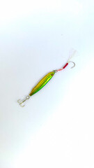 Colorful metal jig fishing lure with assist hook on isolated white background. Top view. Fishing bait.