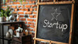 © Michael - Startup message and star symbol written on a blackboard leaning against an office brick wall