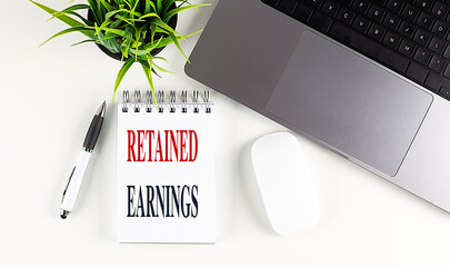 Poster - RETAINED EARNINGS text on a notebook with laptop, mouse and pen .