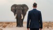 © weerasak - A businessman stands in awe before a majestic elephant on an open landscape, capturing the essence of nature and urban life.