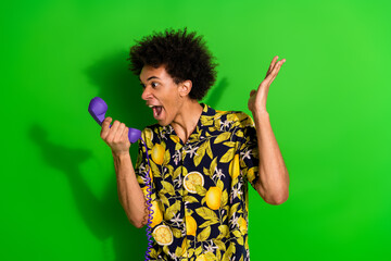 Poster - Photo of aggressive crazy man wear stylish print clothes speak scream phone isolated on green color background