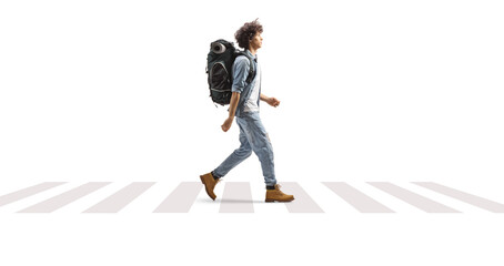 full length profile of a young male traveler walking with a backpack at a pedestrian crossing