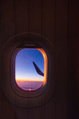 Poster - Airplane flying over color sky clouds during scenic sunset or sunrise cloudscape, view from plane window of wing turbines and horizon