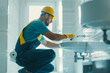 © forenna - Professional plumber repairing bathroom sink pipes: kneeling handyman in work uniform, home maintenance service