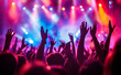 © Curioso.Photography - A lively concert with a vibrant crowd raising their hands under colorful stage lights and dynamic atmosphere.