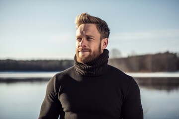 Poster - Portrait of a glad man in his 30s wearing a classic turtleneck sweater while standing against backdrop of a frozen winter lake