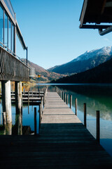 Serene Lakeside View of Wooden Pier With Snow-Capped Mountains in Background