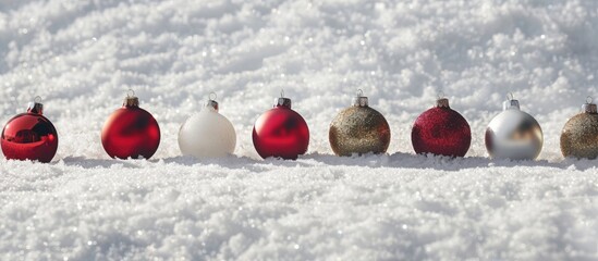 Poster - A row of Christmas ball ornaments placed neatly on snow with copy space image available