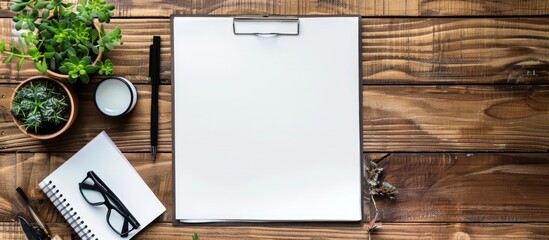 Poster - Minimal flat lay style with a blank paper page on a wooden office desk accompanied by various objects providing a copy space image
