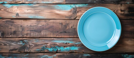 Leinwandbilder - Wooden background with an empty blue plate ideal for a copy space image