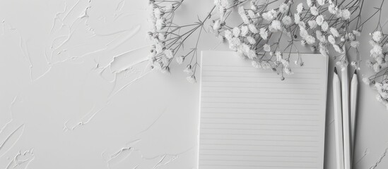 Sticker - Monochrome desk with a lined up notebook pencils and a blank area for text Includes mockup and copy space image viewed from the top with white flowers