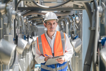 Engineers inspect gas and water pipes for power and cooling in industrial and building systems. workers in safety gear work seriously in oil and gas refining plant with pipes connecting to machinery.