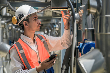 Engineers inspect gas and water pipes for power and cooling in industrial and building systems. workers in safety gear work seriously in oil and gas refining plant with pipes connecting to machinery.