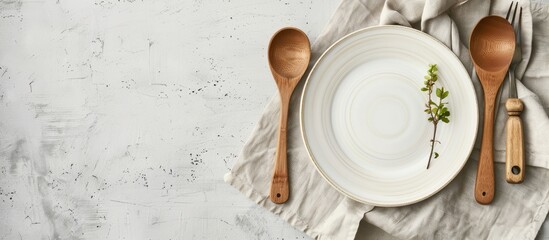 Canvas Print - Rustic vintage dining set with a wooden spoon fork and white plate on a napkin made from water hyacinth against a light gray concrete background with an empty plate perfect for a copy space image in