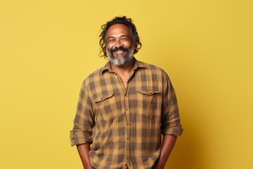 Canvas Print - Portrait of a content indian man in his 50s wearing a comfy flannel shirt isolated in pastel yellow background