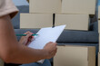 © virojt - A young woman is checking items as they are moved into her new house.