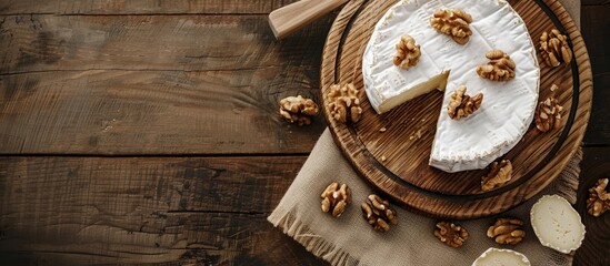 Aufkleber - Top view of sliced round Camembert cheese on a wooden board with nuts in rustic style and natural light with a vintage burlap napkin background featuring a copy space image