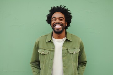 Canvas Print - Portrait of a happy afro-american man in his 30s sporting a rugged denim jacket while standing against pastel green background