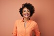 © Markus Schröder - Portrait of a joyful afro-american woman in her 40s donning a classy polo shirt while standing against pastel orange background