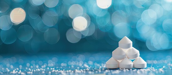 Aufkleber - Foreground close up of white pills forming a pyramid on a blue backdrop with soft bokeh providing copy space image
